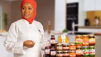 Nimota poses for a photo next to a display table full of her hand-crafted sauces.